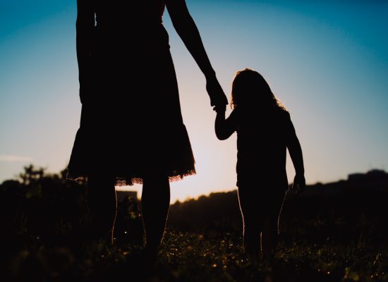 silhouette of mother and daughter holding hands at sunset nature